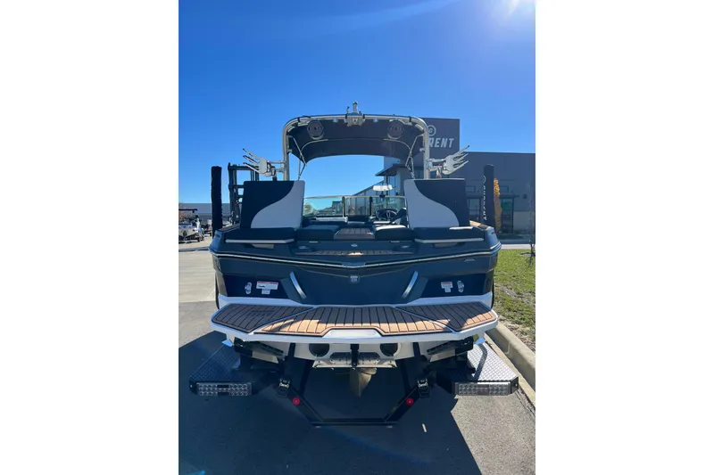 Slide: The Image of 2020 MasterCraft XT23 boat, rear view, parked outdoors under clear blue sky. - 13