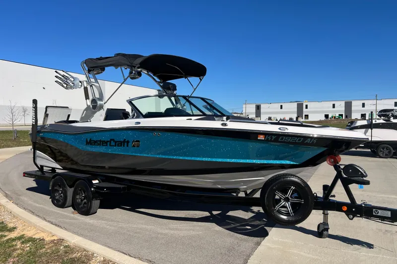 Slide: The Image of 2020 MasterCraft XT23 boat with blue and black design on a trailer, parked outdoors. - 4
