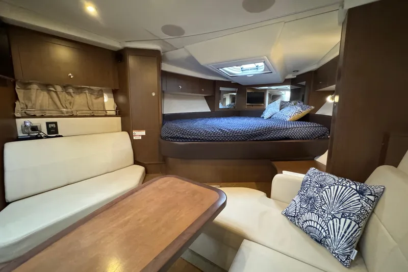 Slide: The Image of 2018 Sea Ray Sundancer 350 Coupe interior with cozy seating and elegant bedding. - 12