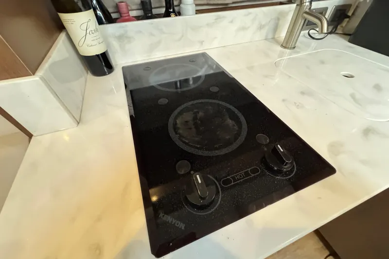 Slide: The Image of Kenyon stove on Sea Ray Sundancer 350 Coupe 2018 yacht, with marble countertop and wine bottle. - 19