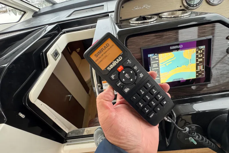 Slide: The Image of Hand holding Simrad remote on 2018 Sea Ray Sundancer 350 Coupe yacht dashboard. - 30