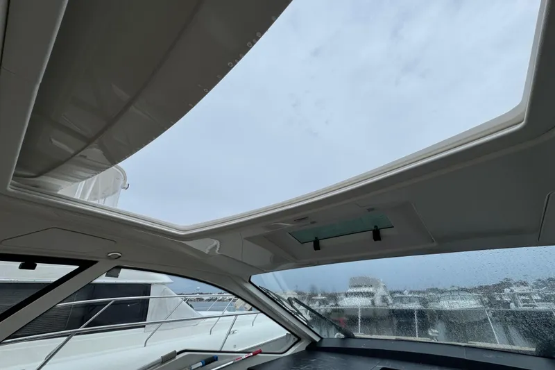 Slide: The Image of 2018 Sea Ray Sundancer 350 Coupe interior with open sunroof, showcasing marina view. - 71