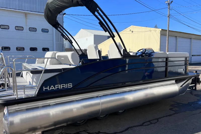 Slide: The Image of 2026 Harris 210 Cruiser SLDH pontoon boat parked outdoors near industrial buildings. - 33