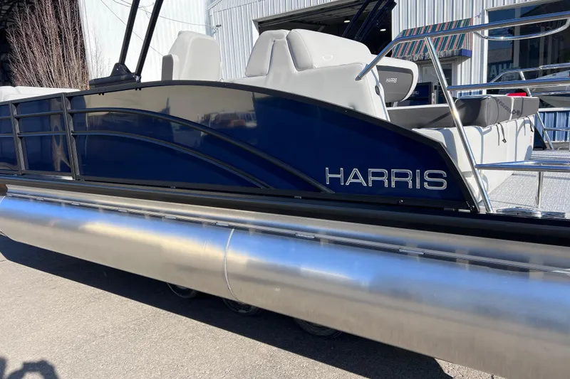 Slide: The Image of 2026 Harris 210 Cruiser SLDH pontoon boat, sleek design, blue exterior, docked outdoors. - 4