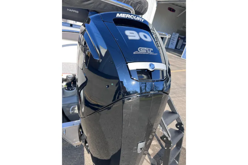 Slide: The Image of 2026 Harris 210 Cruiser SLDH with Mercury 90 CT outboard engine, parked outdoors. - 6