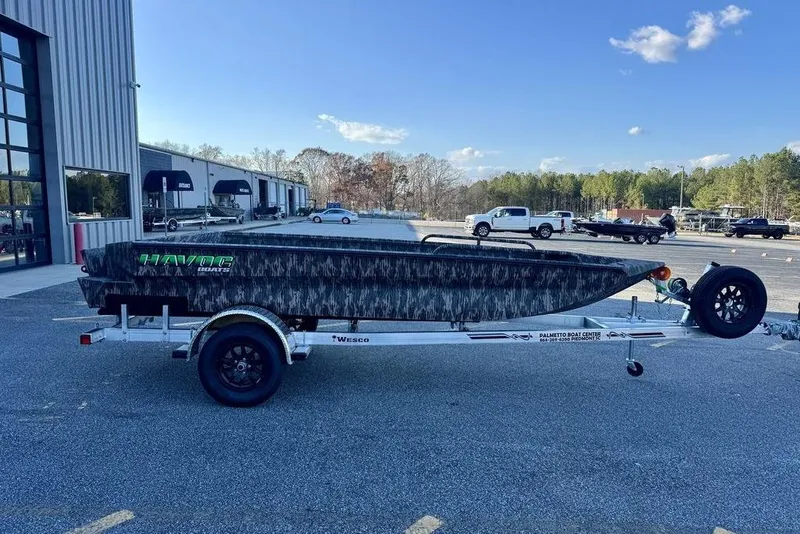 The Image of 2026 Havoc 1756 boat on trailer, parked outside dealership under clear blue sky. - 0