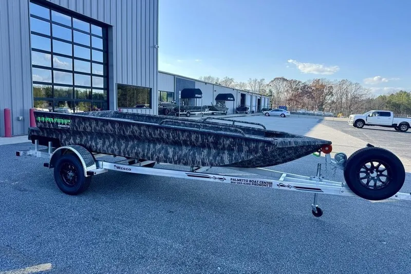 Slide: The Image of 2026 Havoc 1756 boat on trailer outside dealership, featuring camo design and modern build. - 2
