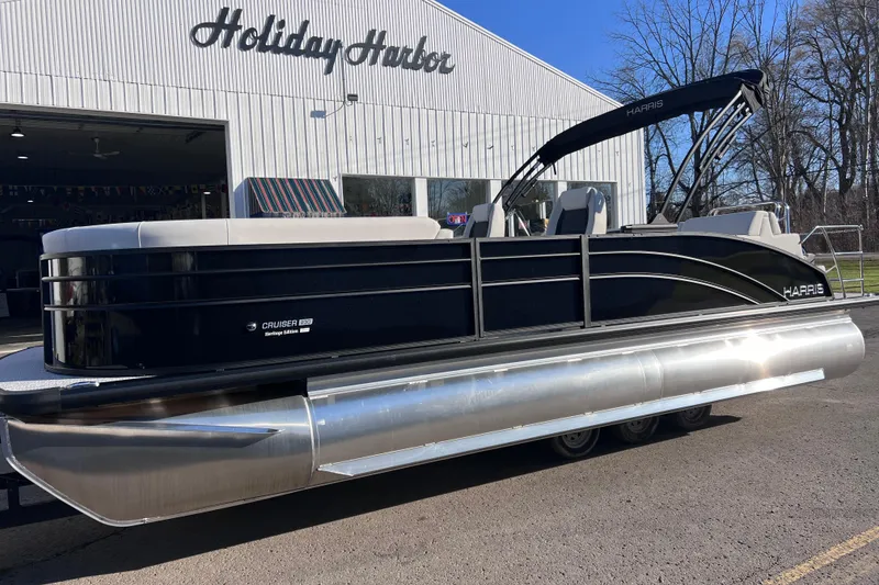 Slide: The Image of 2026 Harris Cruiser 230 SLDH Tritoon boat parked outside Holiday Harbor. - 2
