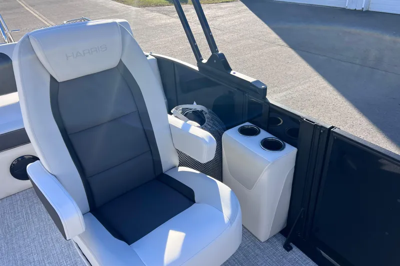 Slide: The Image of 2026 Harris Cruiser 230 SLDH Tritoon boat seat with cup holders, outdoor setting. - 21