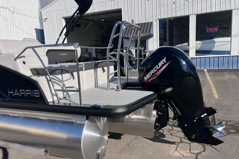 Slide: The Image of 2026 Harris Cruiser 230 SLDH Tritoon with Mercury engine, parked outside a building. - 4