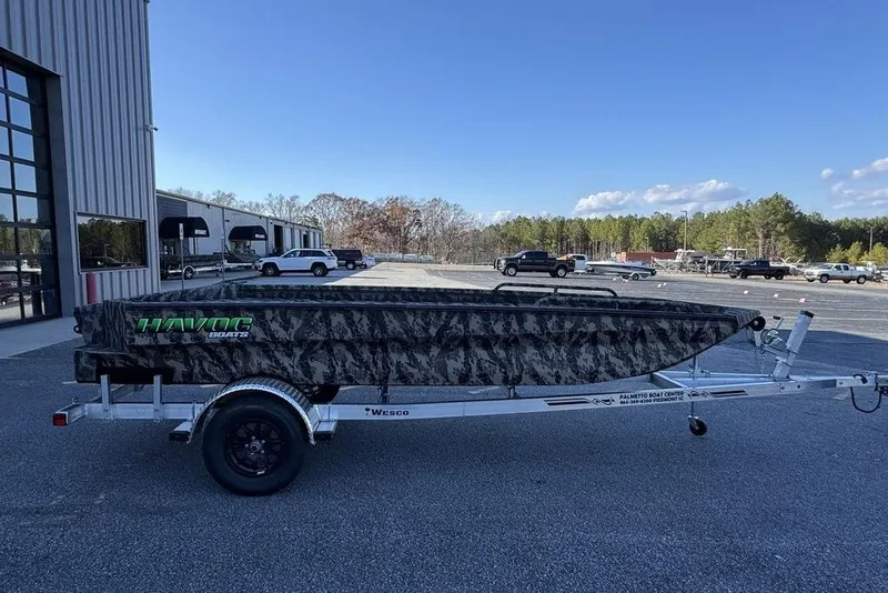 The Image of 2025 Havoc 1860 boat on trailer, camo design, parked outside dealership. - 1