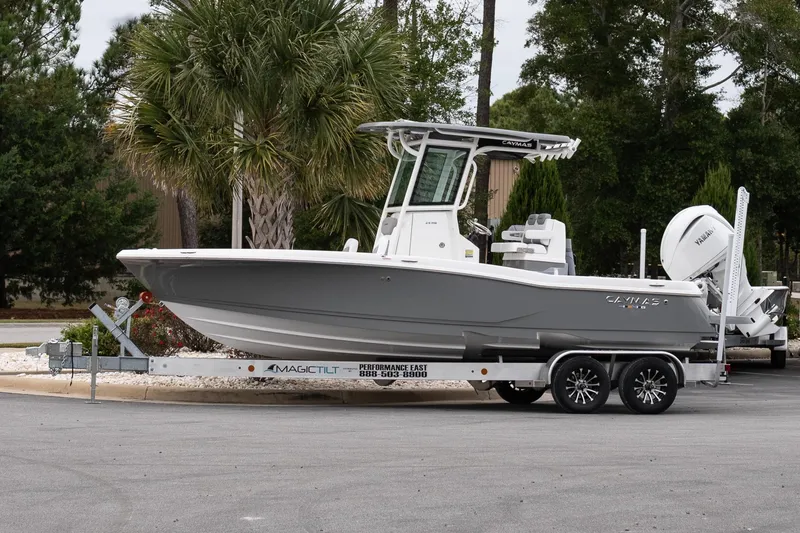 The Image of 2026 Caymas 24 HB boat on trailer, parked outdoors with trees in background. - 1