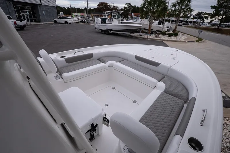 Slide: The Image of 2026 Caymas 24 HB boat interior with cushioned seating, parked at a dealership. - 17
