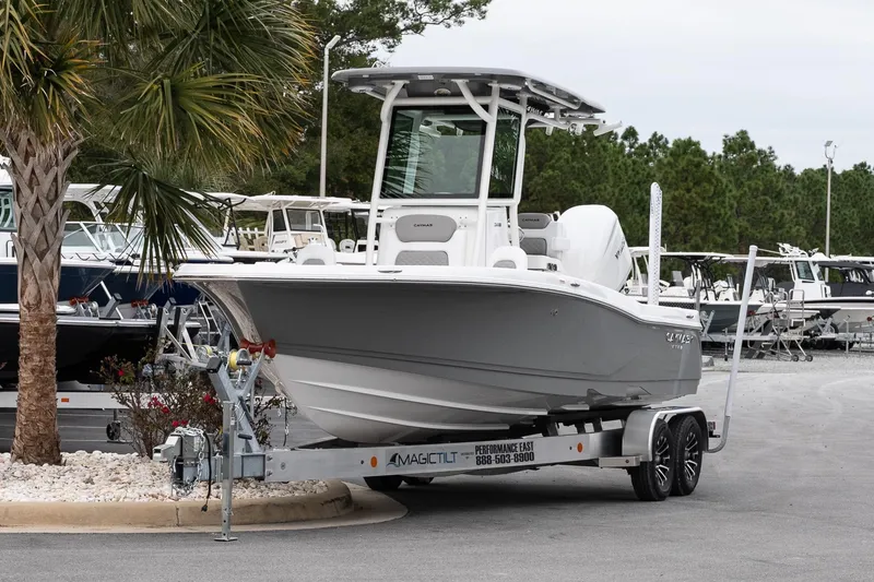 Slide: The Image of 2026 Caymas 24 HB boat on trailer, parked near palm tree in marina. - 3