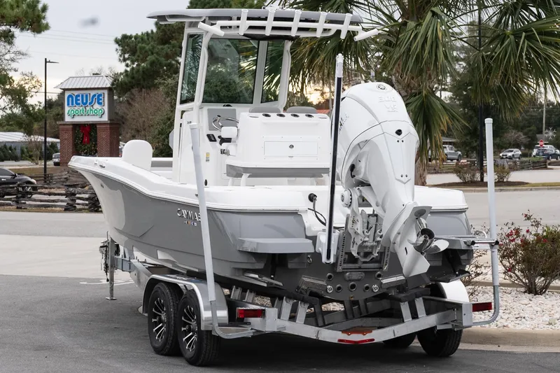Slide: The Image of 2026 Caymas 24 HB boat on trailer, parked near Neuse Sport Shop, surrounded by palm trees. - 5