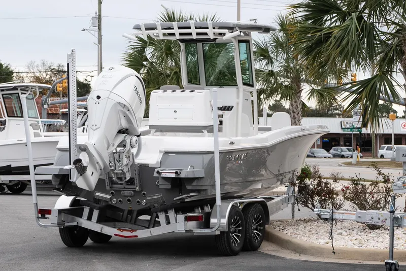Slide: The Image of 2026 Caymas 24 HB boat on trailer, featuring Yamaha outboard motor, parked near palm trees. - 7