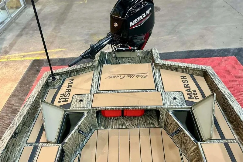 Slide: The Image of 2026 Tracker Grizzly 1756 T Marsh boat with Mercury engine, camo design, and open storage compartments. - 12