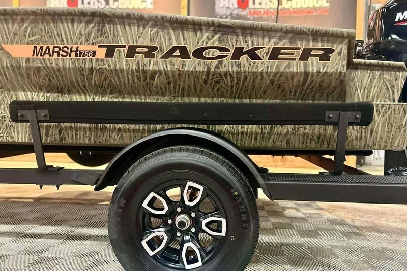 Slide: The Image of 2026 Tracker Grizzly 1756 T Marsh boat trailer with camo design and black wheel. - 16