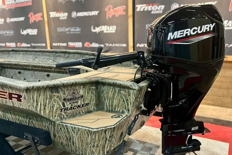 Slide: The Image of 2026 Tracker Grizzly 1756 T Marsh boat with Mercury outboard motor displayed indoors. - 4