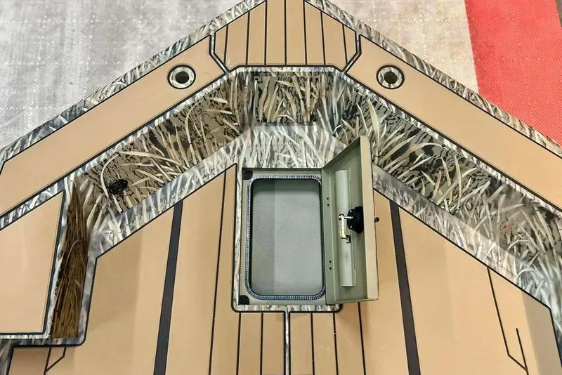 Slide: The Image of 2026 Tracker Grizzly 1756 T Marsh boat deck with open storage compartment, camo design. - 5