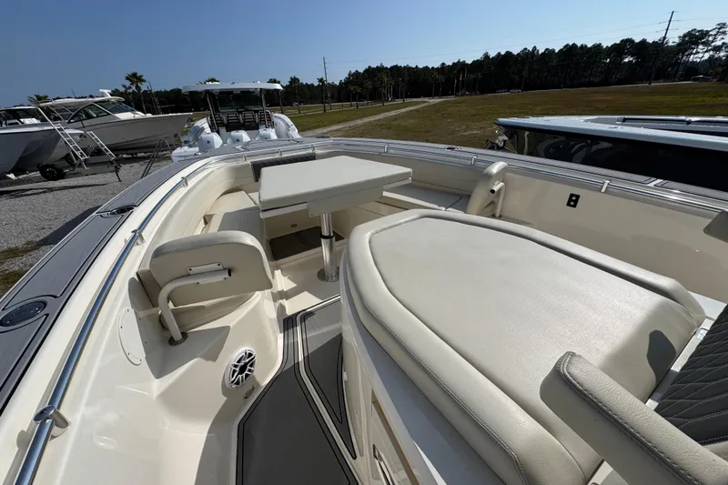 Slide: The Image of 2022 Cobia 350 Center Console boat interior with seating and table, docked outdoors. - 14