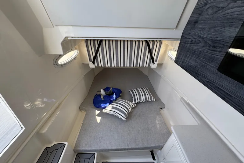 Slide: The Image of 2022 Cobia 350 Center Console cabin interior with striped cushions and portholes. - 24