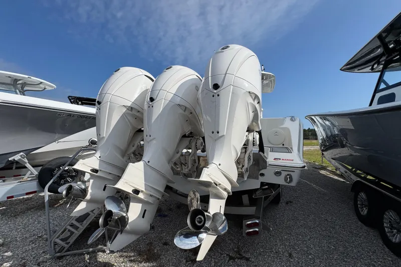Slide: The Image of 2022 Cobia 350 Center Console with triple outboard engines, parked on gravel. - 8