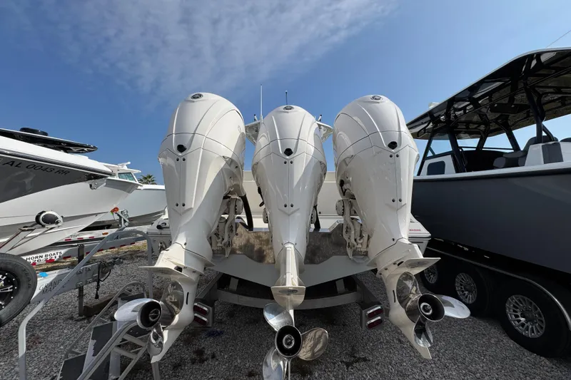 Slide: The Image of 2022 Cobia 350 Center Console with triple outboard engines, parked on gravel. - 9