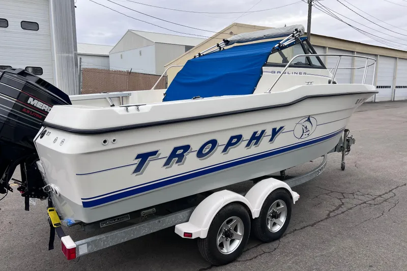 Slide: The Image of 1993 Bayliner Trophy Walkaround boat on trailer, featuring blue cover and Mercury engine. - 10