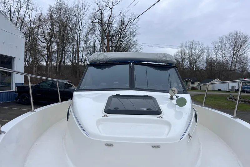 Slide: The Image of 1993 Bayliner Trophy Walkaround boat with windshield, docked outdoors on a cloudy day. - 12