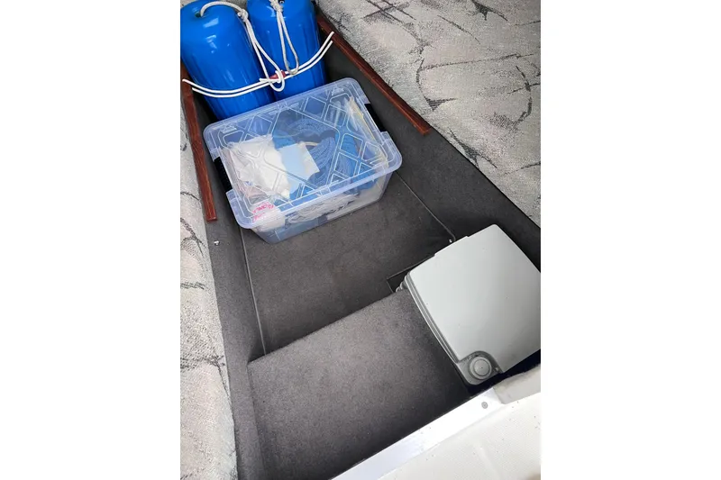 Slide: The Image of Storage compartment of 1993 Bayliner Trophy Walkaround with blue fenders and a clear plastic container. - 21