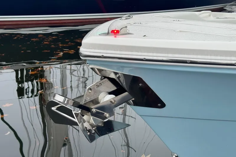 Slide: The Image of 2024 Cobia 240 Dual Console boat with anchor and navigation light on calm water. - 13