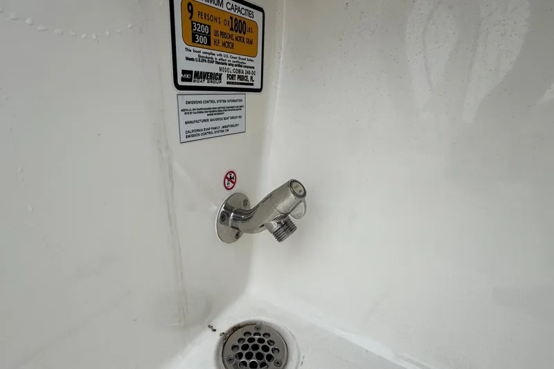 Slide: The Image of Cobia 240 Dual Console 2024 boat drain and capacity label detail. - 22