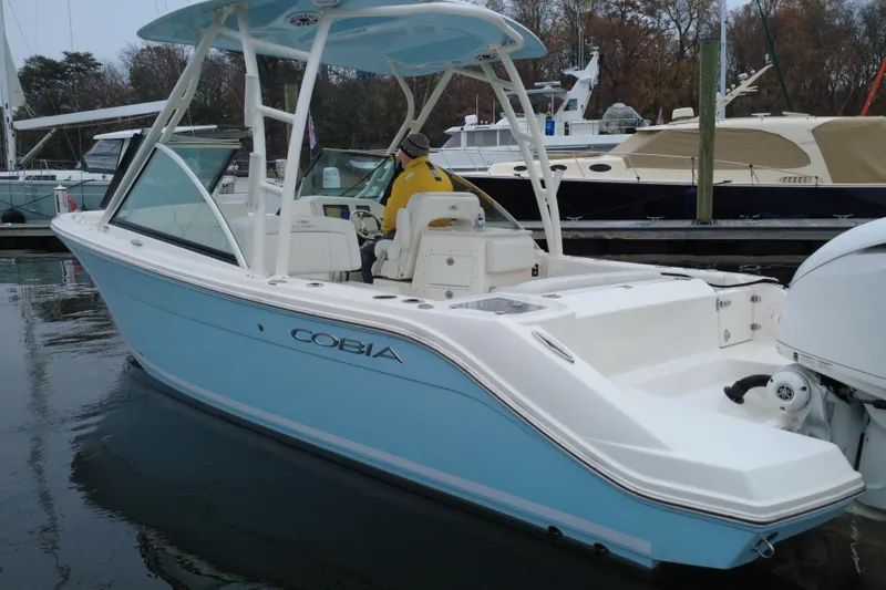 Slide: The Image of 2024 Cobia 240 Dual Console boat docked, featuring sleek design and light blue hull. - 5