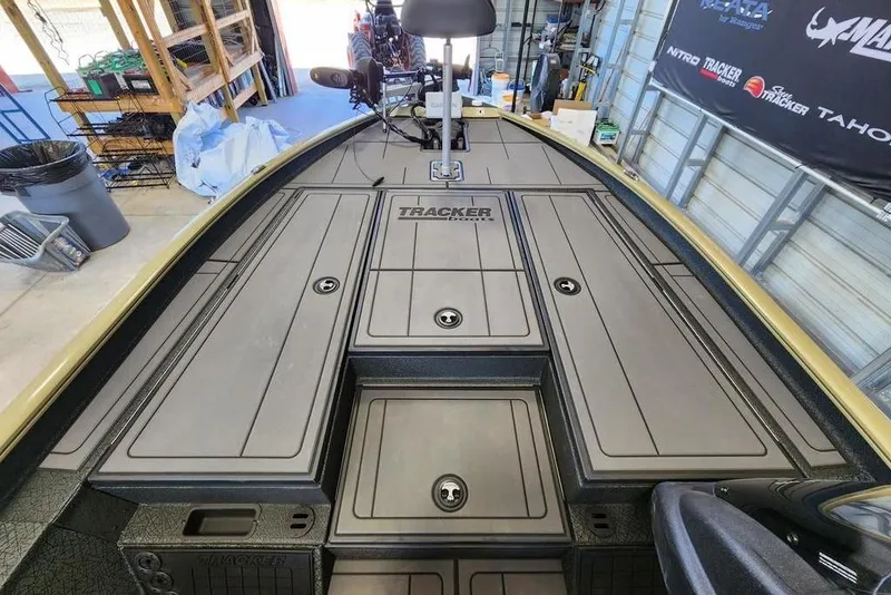 Slide: The Image of 2026 Tracker Savage 215 boat deck in a garage, showcasing storage compartments and equipment. - 10