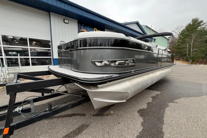 Slide: The Image of 2026 Avalon Catalina Versatile Rear Bench pontoon boat on trailer, parked outside a building. - 8