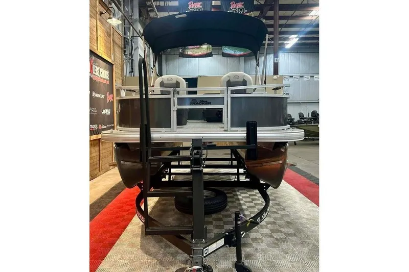 Slide: The Image of 2026 Sun Tracker Bass Buggy 16 XL Select pontoon boat in showroom, front view. - 16