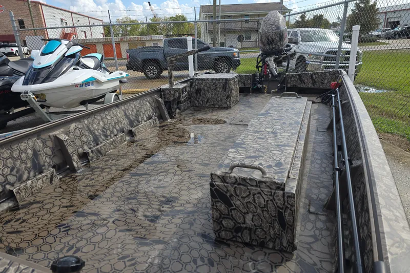 Slide: The Image of 2026 Pro-Drive 1854 boat with camouflage interior, parked near jet skis and vehicles. - 8