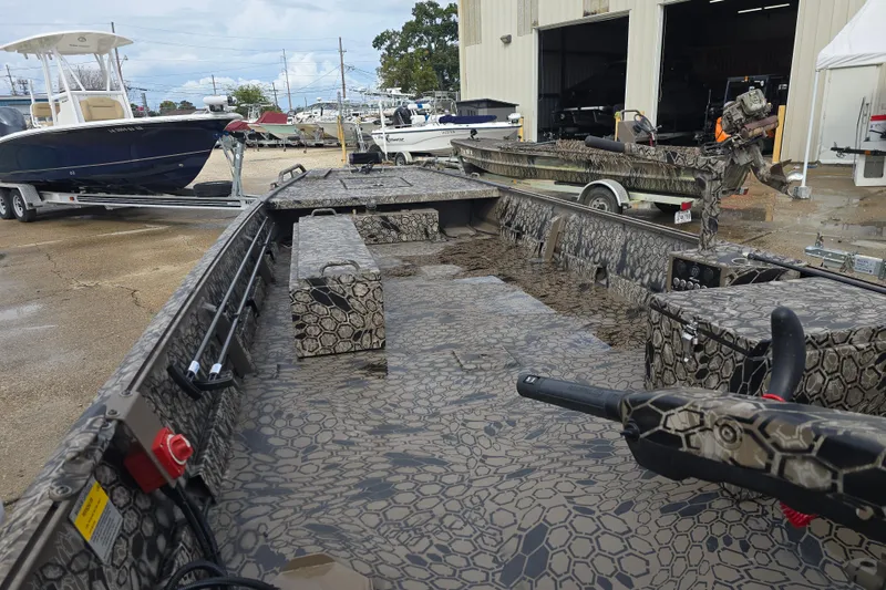 Slide: The Image of 2026 Pro-Drive 1854 boat with camouflage pattern, parked near a workshop. - 9