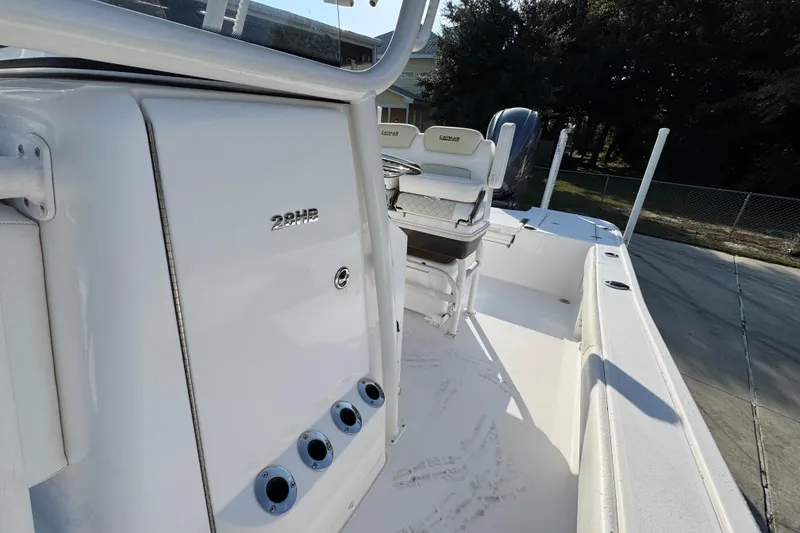 Slide: The Image of 2020 Caymas 28 HB boat interior with seating and control panel, docked outdoors. - 25