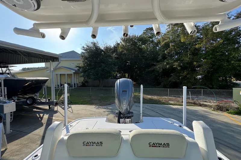Slide: The Image of 2020 Caymas 28 HB boat with outboard motor, docked near a house and trees. - 29