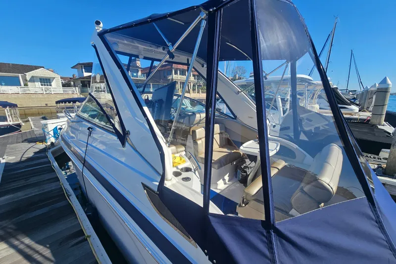 Slide: The Image of 2013 Regal 28 Express boat docked, featuring a blue canopy and spacious seating area. - 10