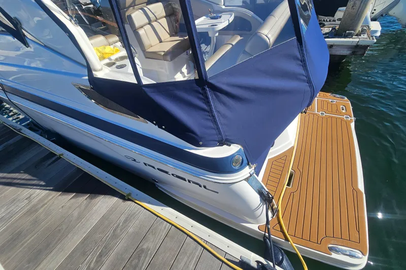 Slide: The Image of 2013 Regal 28 Express boat docked with blue cover and wooden deck. - 11