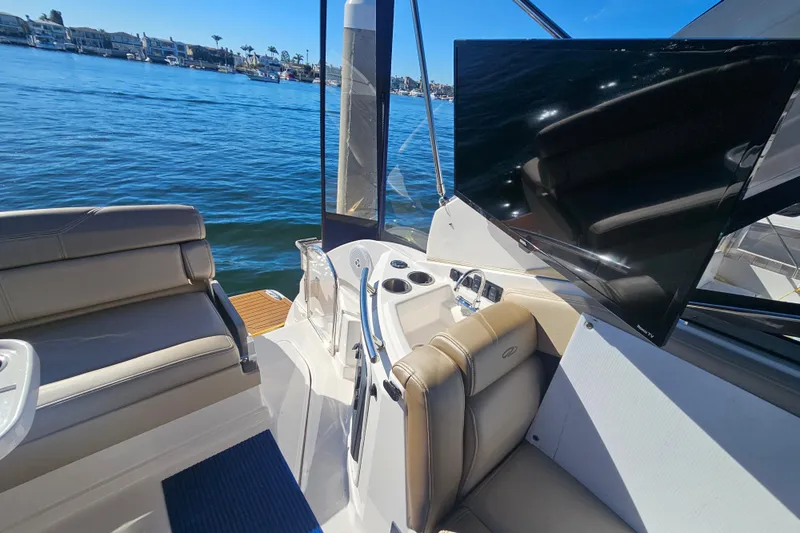 Slide: The Image of 2013 Regal 28 Express boat interior with seating, TV, and water view. - 13