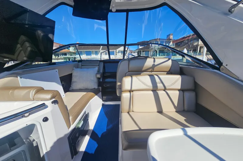Slide: The Image of 2013 Regal 28 Express boat interior with beige seating and a mounted TV. - 17