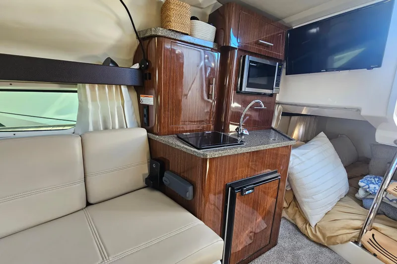 Slide: The Image of 2013 Regal 28 Express cabin interior with kitchenette, seating, and sleeping area. - 27