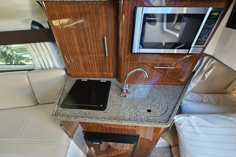 Slide: The Image of 2013 Regal 28 Express boat interior with kitchenette, featuring microwave and sink. - 28