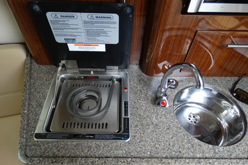 Slide: The Image of 2013 Regal 28 Express boat kitchen with stove and sink on granite countertop. - 29