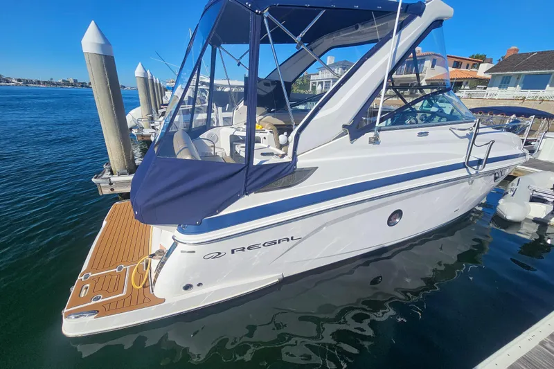 Slide: The Image of 2013 Regal 28 Express boat docked, featuring sleek design and blue canopy. - 8