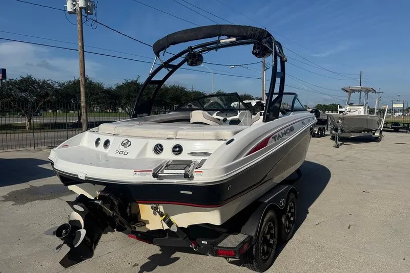 Slide: The Image of 2018 Tahoe 700 TF boat on trailer, parked outdoors under clear blue sky. - 5